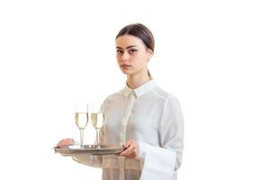 Beautiful brunette waitress in uniform holding a trey with wine photo