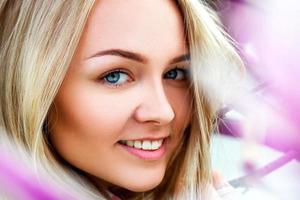 Beauty young blonde smiling near pink blooming flowers photo