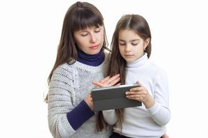 young mother and her daughter sit together and look at the Tablet is isolated on a white background photo