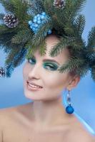 Pretty young girl looking at camera in studio with christmas tree-wreath on head photo