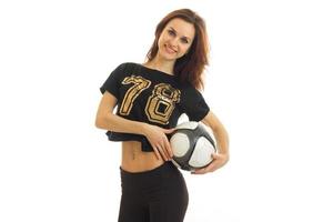 the charming, smiling girl in black t-shirt with numbers looks straight and holds the ball photo