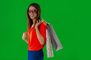 mujer joven con gafas sonriendo a la cámara con una bolsa de compras en las manos foto