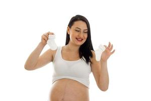 studio portrait of young pregnant brunette woman with little socks in her hands isolated on white background photo