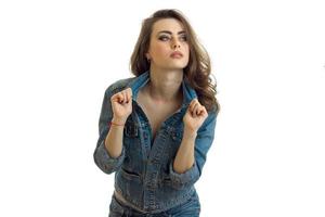 young charming brunette leaned forward in a jeans jacket looks away and keeps hands collar photo