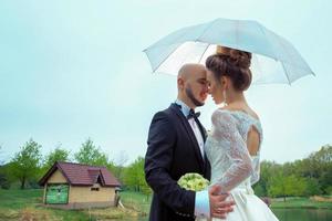 joven pareja casada sonriendo el uno al otro bajo el paraguas foto