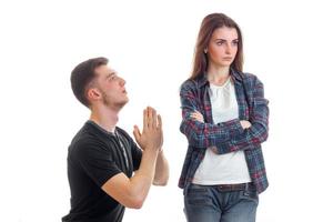 young guy kneels before the girl keeps the palms together and asks forgiveness photo