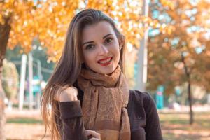 beautiful girl with red lipstick and a Brown scarf stands in the Park  smiles photo