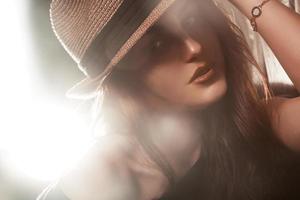 Stylish young adult woman in hat looking at camera. Studio shot photo