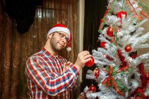 nerd en sombrero de santa decorar el árbol de navidad foto