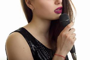 portrait of a young brunette with a microphone is isolated on a white background photo