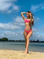 sexy woman in pink swimsuit posing on the beach photo