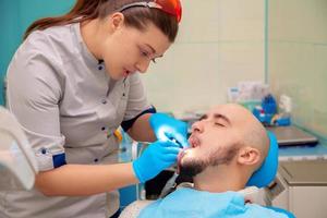 beautiful male model treats caries teeth in the dental office photo