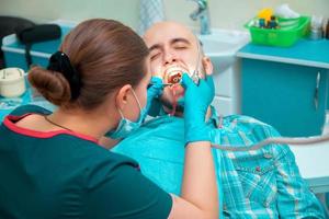 el dentista inserta al tipo de la dentadura postiza en el consultorio dental foto