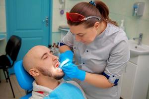 chico guapo en el consultorio dental trata los dientes foto