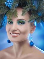 Charming young woman smiling in studio with xmas tree-wreath on head photo