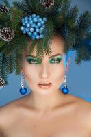 Serious young woman with nice makeup and xmas tree-wreath on head looking at camera photo