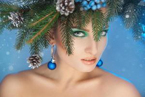 Beautiful young woman with tree-wreath on head and nice makeup at christmas time photo