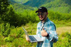 male model working in the mountains on a laptop photo