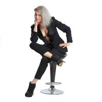 mujer con cabello rizado rubio en traje de negocios negro se sienta en una silla foto
