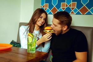 niña alimentando a su novio con una hamburguesa foto