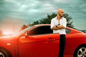 hombre elegante con coche deportivo rojo foto