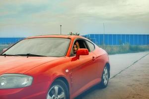 mujer con labios rojos conduciendo un auto rojo foto