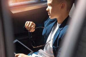 rich boy sits on a backseat of car photo