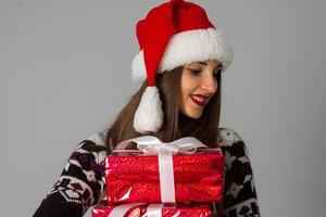 mujer en suéter cálido y sombrero de santa con regalo rojo foto