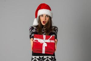 woman in warm sweater and santa hat with red gift photo