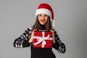 woman in warm sweater and santa hat with red gift photo