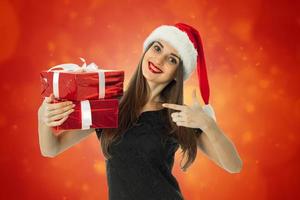 Cheerful Woman in santa hat with red gift photo
