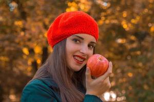 beautiful girl with a Red Hat smiles and keeps Apple in hand photo