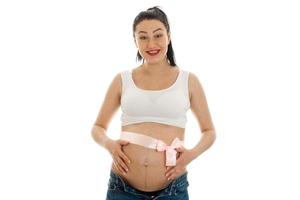 Young cheerful pregnant mother with pink tape on belly isolated on white background in studio posing photo