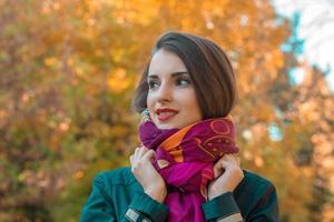 cute girl stands in the park looks away and keeps hands scarf photo