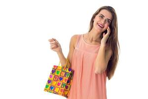 jovencita con vestido brillante sosteniendo una bolsa colorida y mirando hacia otro lado foto