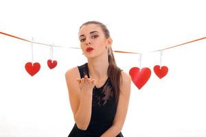 Una joven encantadora con labios rojos preparándose para celebrar el día de San Valentín con el símbolo del corazón en un estudio aislado de fondo blanco