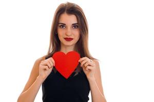 mujer morena joven sexy con corazón rojo en manos posando aislado sobre fondo blanco. concepto del día de san valentín. concepto de amor foto