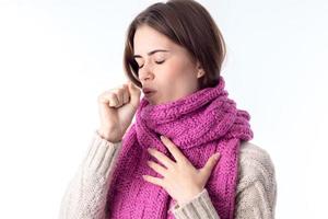 girl in a warm scarf coughs closing eyes is isolated on  white background photo