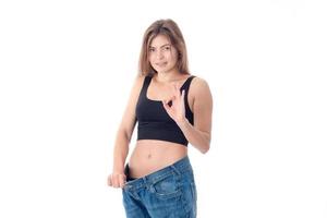 Slim young girl in black top stands in the large size trousers isolated on white background photo