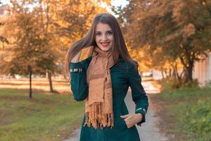 young girl in  long scarf smiles while standing in the Park photo