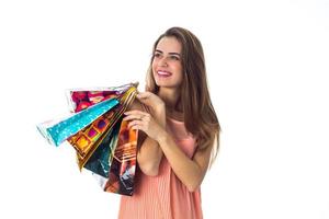 hermosa niña se ríe y sostiene grandes bolsas multicolores aisladas sobre fondo blanco foto