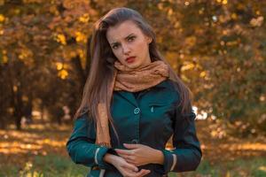serious young girl in a black jacket stands in autumn Park photo