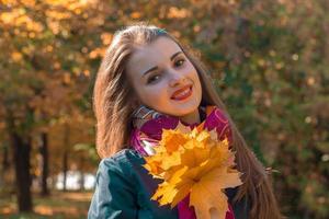 good beautiful girl stands on the street and keeps the leaves photo