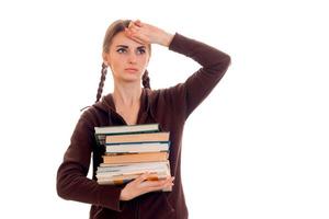 tired young students girl with a lot of books in her hands isolated on white background photo