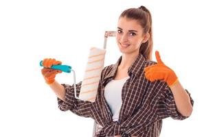 pretty young slim builder girl makes renovations with paint roller isolated on white background photo