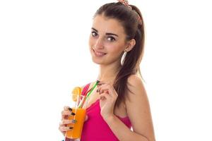 portrait of cheerful young brunette woman drinks orange cocktail and smiling on camera isolated on white background photo