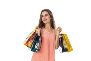 la niña mira a un lado y sostiene las dos manos de bolsas de diferentes colores aisladas en fondo blanco foto