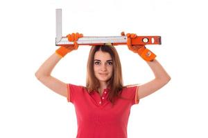 portrait of young beauty brunette building woman in uniform with tools in hands makes renovation and looking at the camera isolated on white background photo