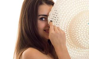 portrait of cheerful young brunette girl with straw hat in her hands smiling on camera isolated on white background photo