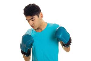 young guy standing in boxing gloves and looking down isolated on white background photo